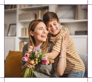 Mother and son sharing a warm hug while holding a bouquet of tulips on the couch